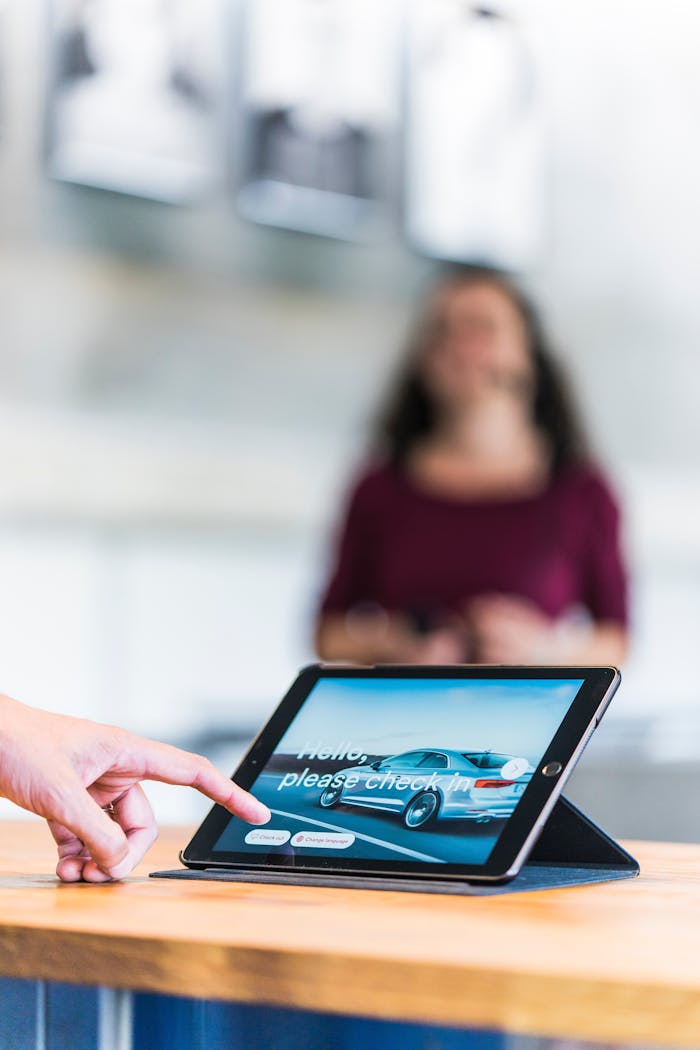 Person checking in on a tablet at a modern office reception with a blurred background.